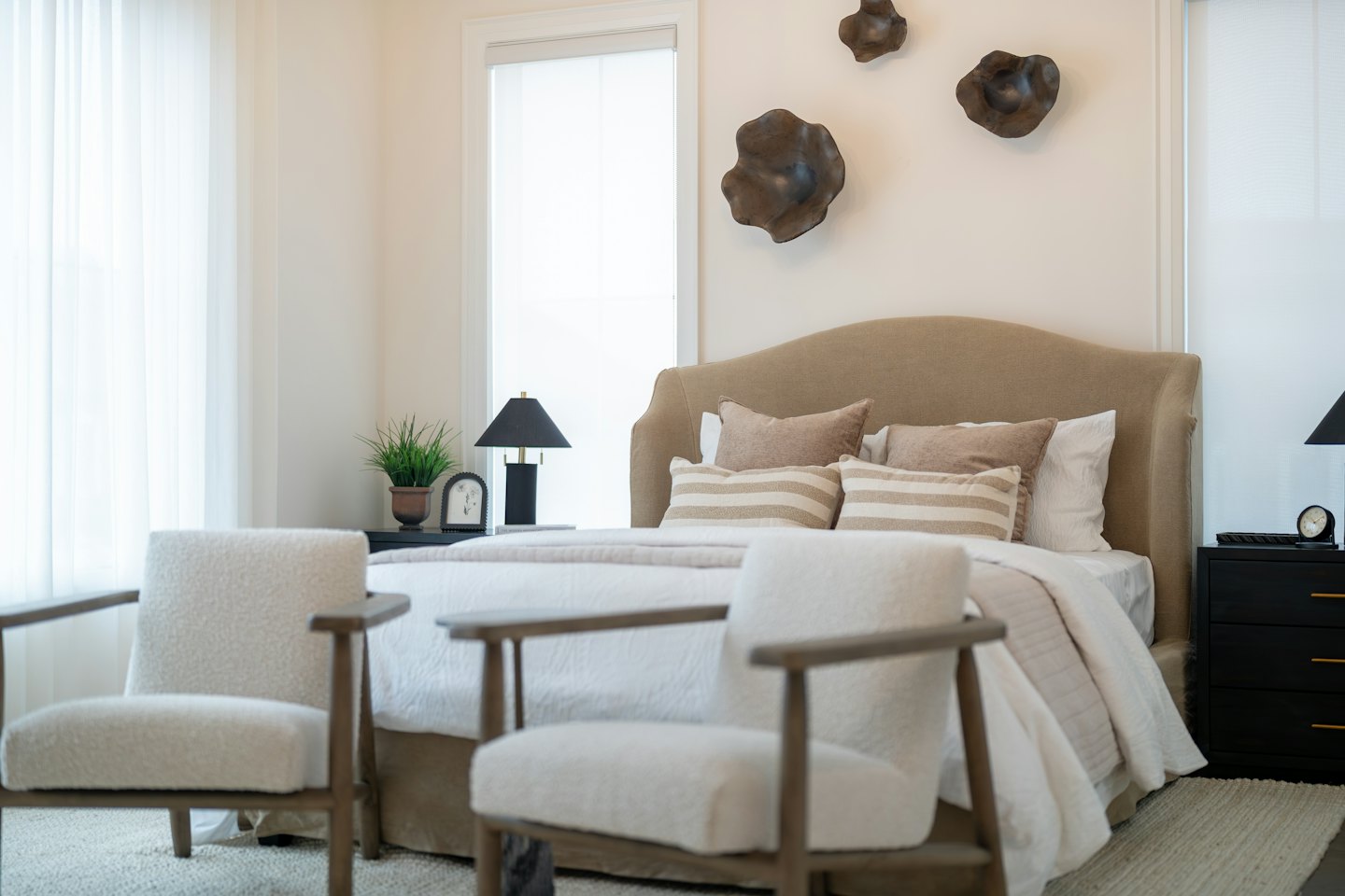 Camera da letto moderna con letto e due poltrone.