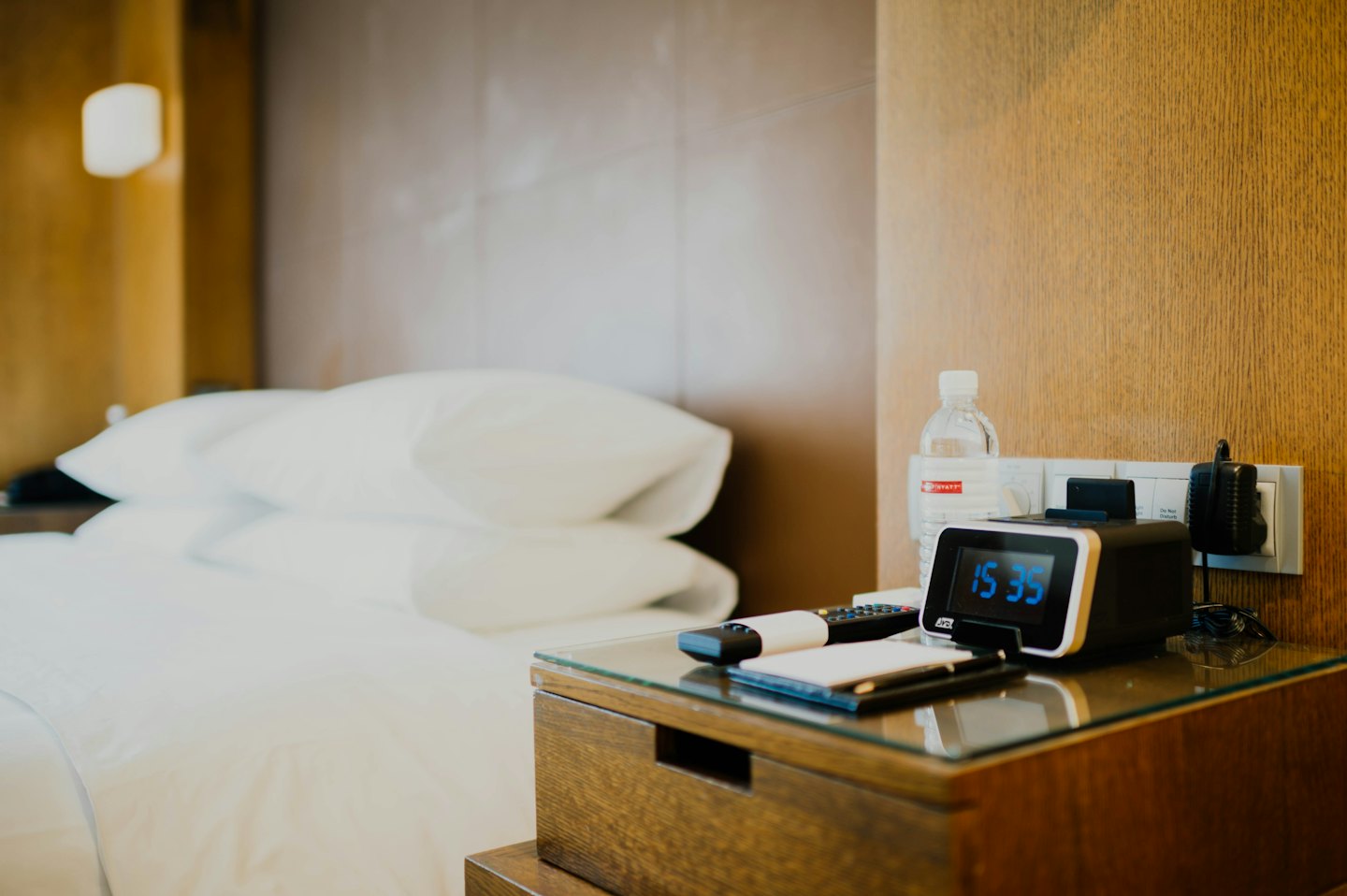 Comodino d'albergo con sveglia e accessori da viaggio.