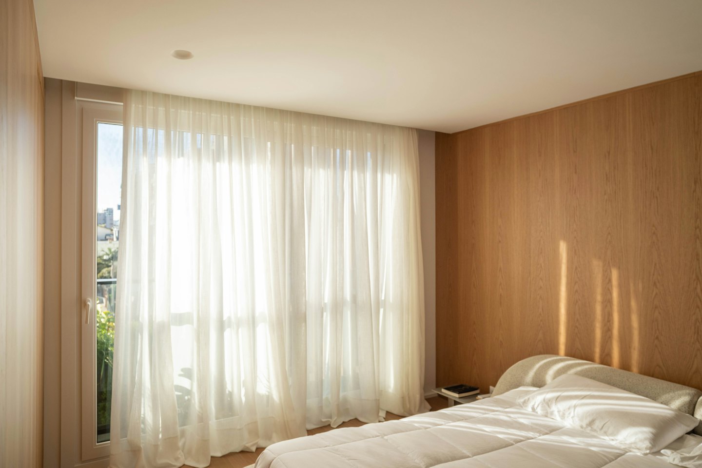 Camera da letto con letto rifatto e luce solare che filtra da una finestra.