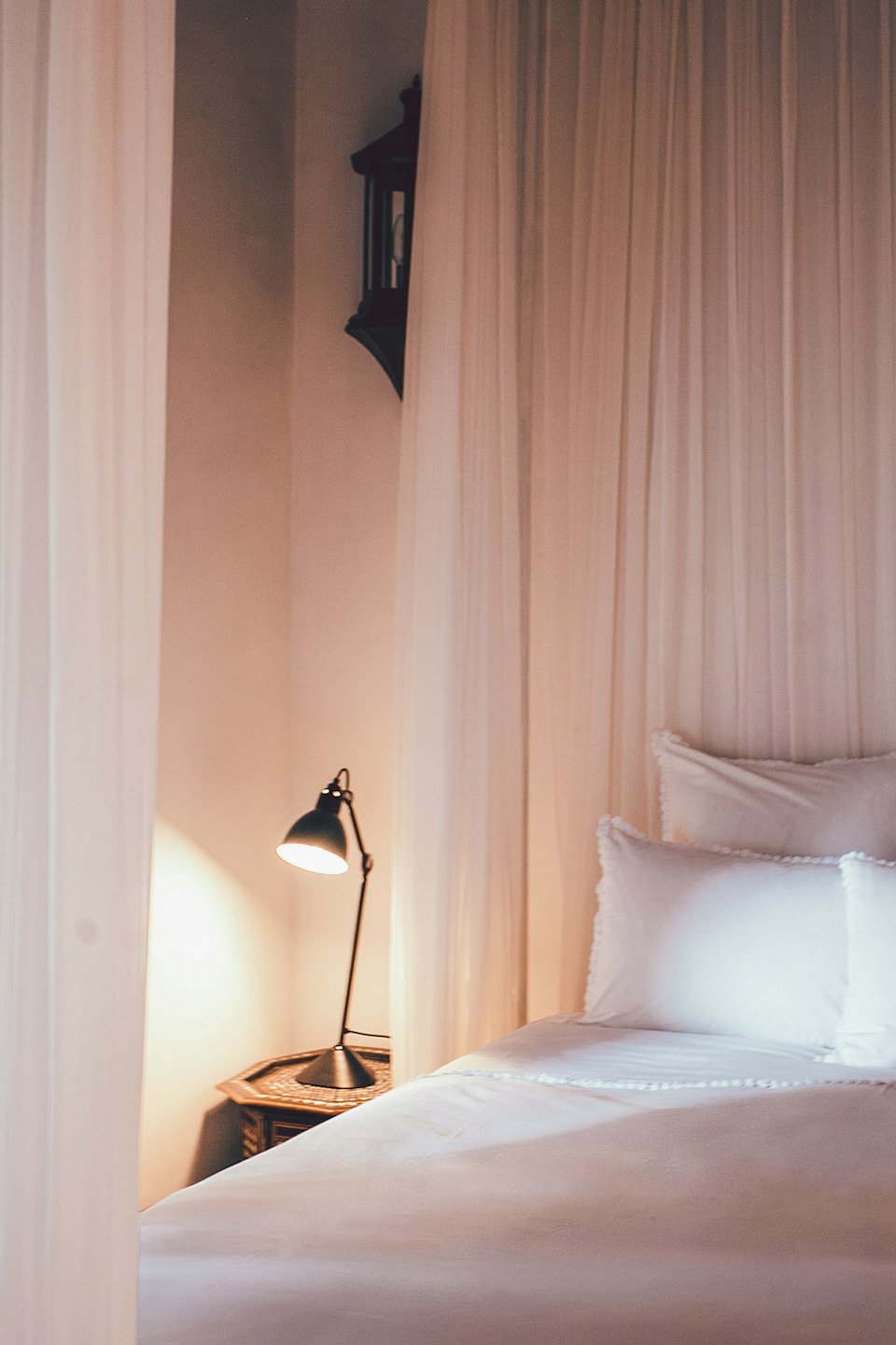 Un letto fatto con lenzuola bianche e un comodino.